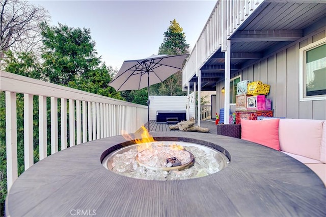 wooden deck with an outdoor fire pit and a hot tub