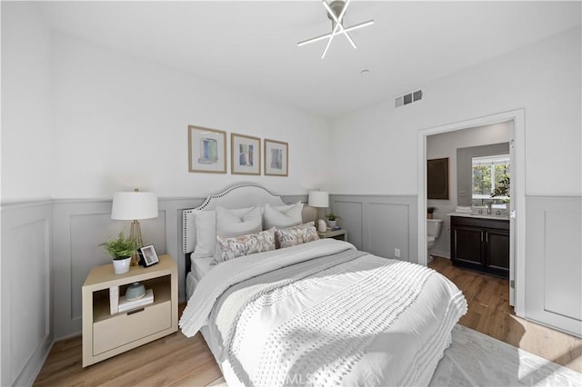 bedroom featuring ensuite bath and hardwood / wood-style floors