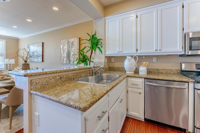 kitchen featuring kitchen peninsula, appliances with stainless steel finishes, white cabinets, and sink