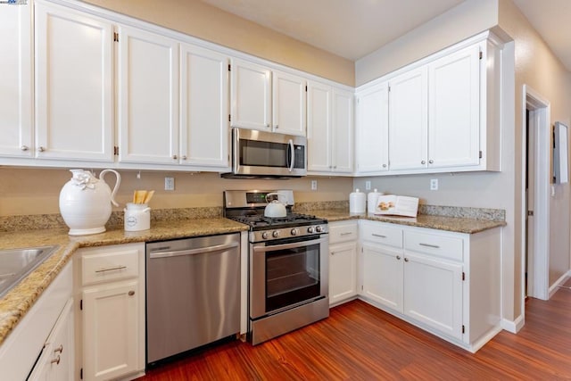 kitchen featuring stainless steel appliances, white cabinetry, light stone counters, and dark hardwood / wood-style floors