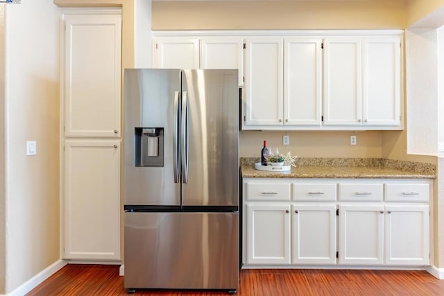 kitchen featuring stainless steel refrigerator with ice dispenser, white cabinets, light wood-type flooring, and light stone counters