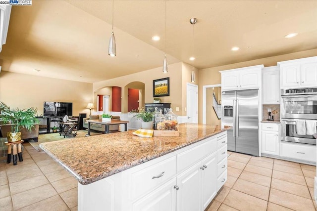 kitchen featuring stainless steel appliances, decorative light fixtures, a center island, white cabinetry, and light tile patterned floors