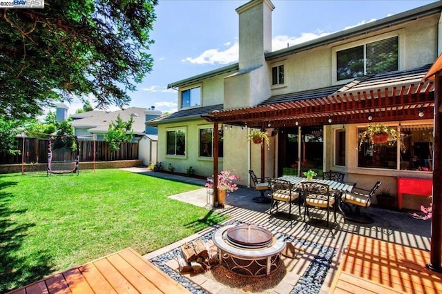 rear view of house with an outdoor fire pit, a yard, a trampoline, and a pergola