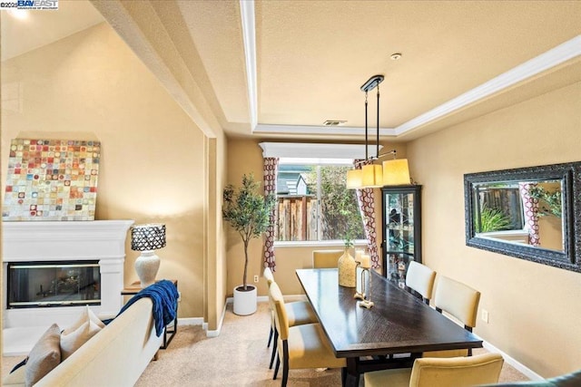 carpeted dining area with a tray ceiling