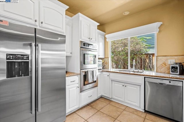 kitchen featuring sink, white cabinetry, light tile patterned floors, and appliances with stainless steel finishes