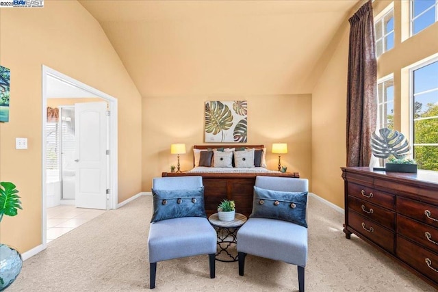 bedroom featuring ensuite bath, light carpet, multiple windows, and vaulted ceiling