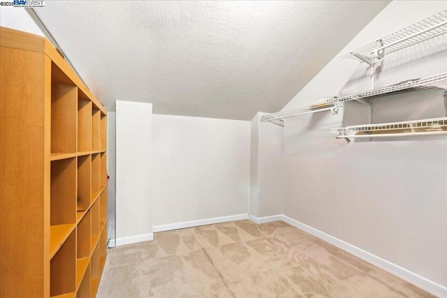 walk in closet with carpet and lofted ceiling