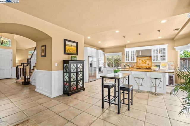 kitchen featuring a kitchen island, a breakfast bar area, stainless steel fridge, and white cabinetry