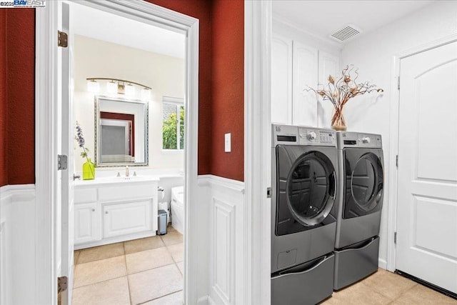 clothes washing area featuring sink, light tile patterned floors, and independent washer and dryer