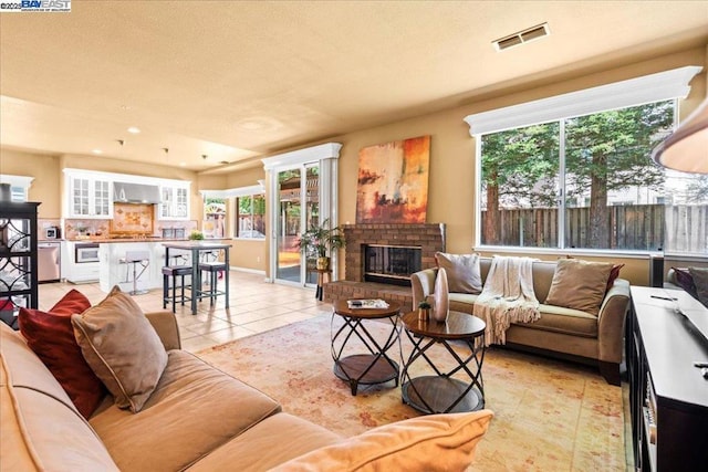 living room featuring light tile patterned flooring and a brick fireplace