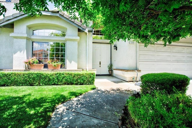 property entrance featuring a garage and a lawn