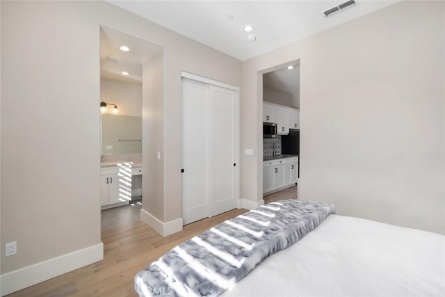 bedroom with a closet, light hardwood / wood-style floors, and connected bathroom