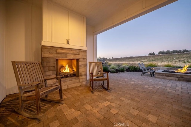 patio terrace at dusk featuring a rural view and an outdoor fireplace