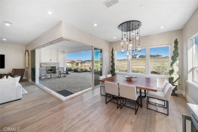 dining space with light wood-type flooring, a wealth of natural light, and an inviting chandelier