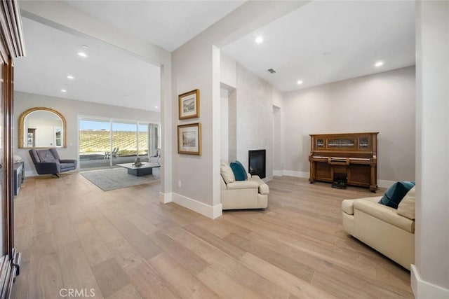 living room with a tile fireplace and light wood-type flooring