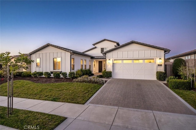 modern inspired farmhouse with a yard and a garage