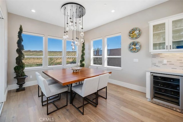 dining room featuring light hardwood / wood-style flooring, beverage cooler, and a chandelier