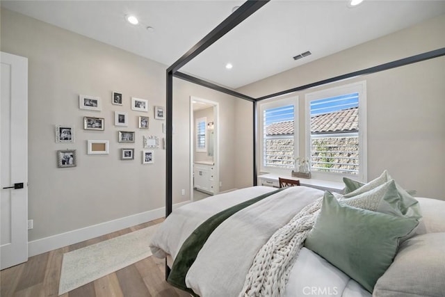 bedroom featuring ensuite bath and light wood-type flooring