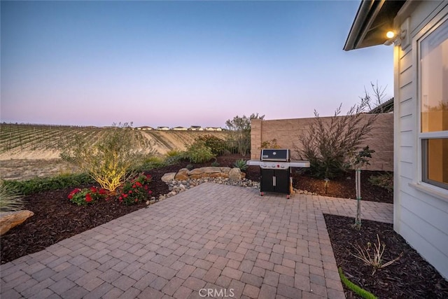 patio terrace at dusk featuring a grill and a rural view