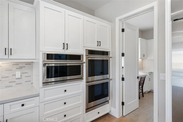 kitchen with stainless steel appliances, white cabinetry, and tasteful backsplash