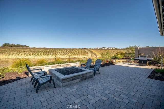 view of patio featuring an outdoor fire pit, a rural view, and area for grilling