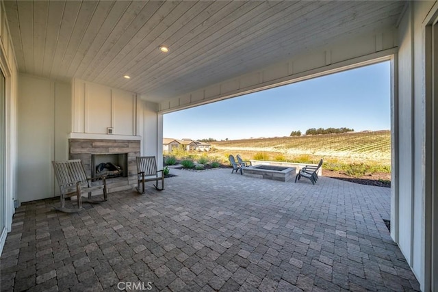 view of patio featuring an outdoor fireplace, a rural view, and an outdoor fire pit