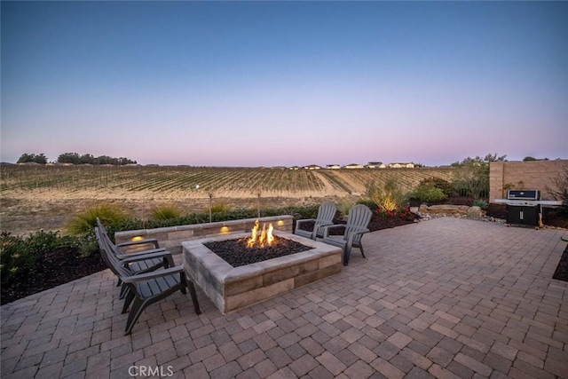 view of patio with area for grilling, a fire pit, and a rural view