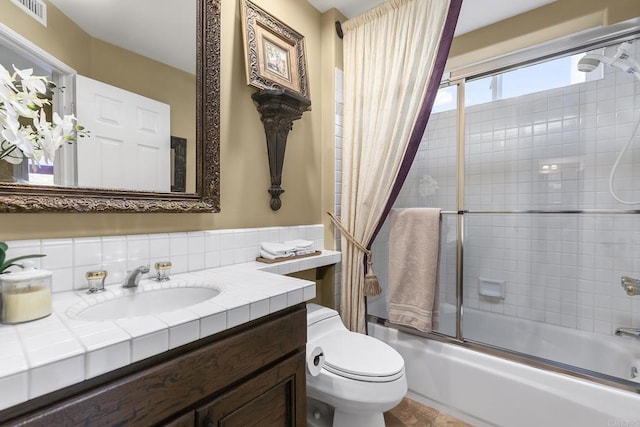 full bathroom featuring toilet, vanity, and bath / shower combo with glass door