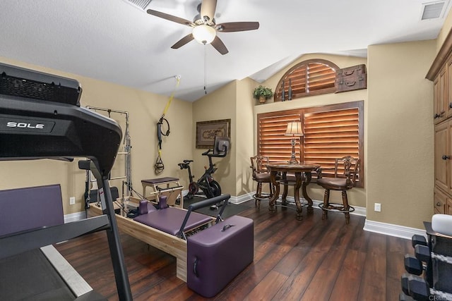 workout area with ceiling fan, vaulted ceiling, and dark hardwood / wood-style floors