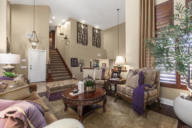 living room with visible vents, a notable chandelier, a high ceiling, baseboards, and stairs