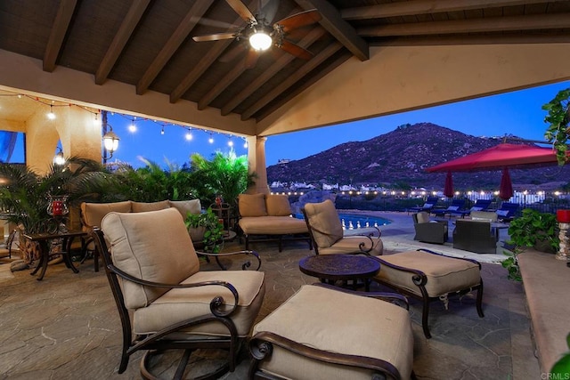 view of patio featuring fence, an outdoor living space, outdoor dining area, ceiling fan, and a mountain view