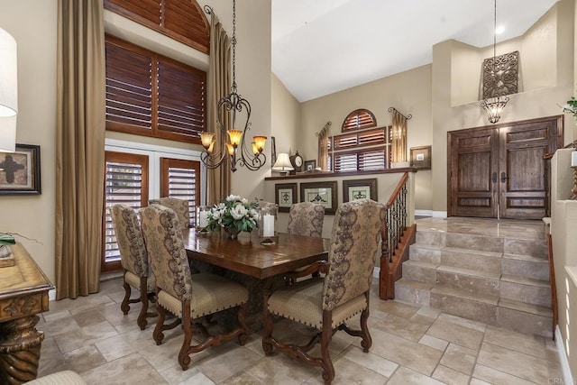 dining space featuring a chandelier, stairway, and a high ceiling