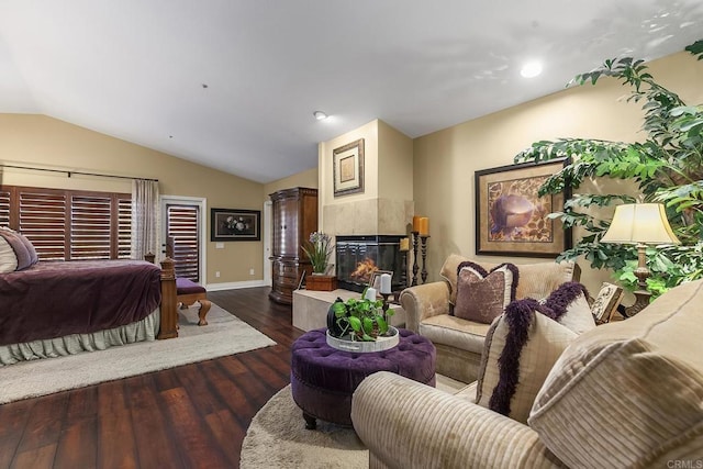 bedroom with baseboards, wood finished floors, a high end fireplace, and vaulted ceiling