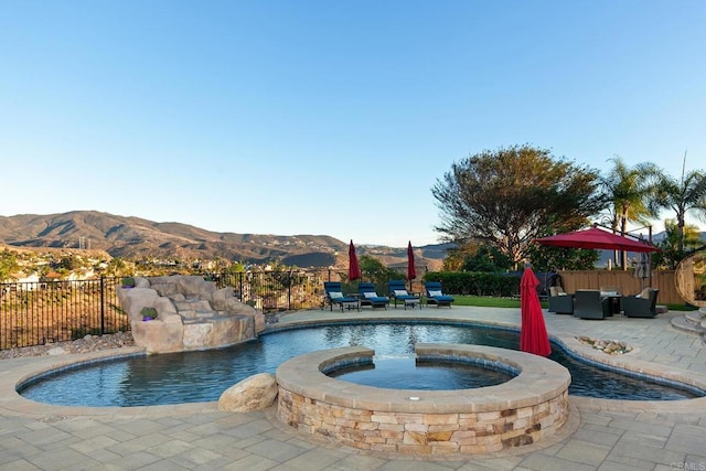 view of pool with a pool with connected hot tub, a fenced backyard, a mountain view, outdoor lounge area, and a patio area