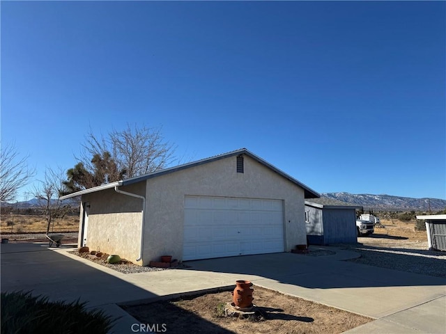 view of home's exterior with a garage, concrete driveway, stucco siding, and a mountain view