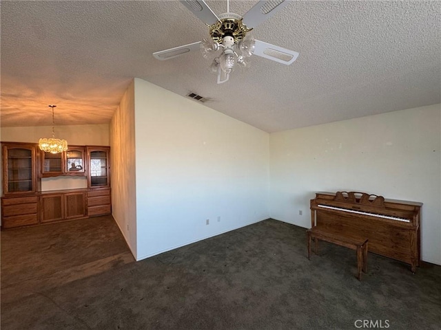 interior space with dark colored carpet, a textured ceiling, visible vents, ceiling fan with notable chandelier, and lofted ceiling