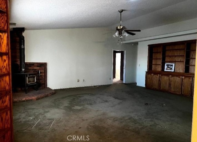 unfurnished living room featuring a wood stove, carpet floors, and ceiling fan