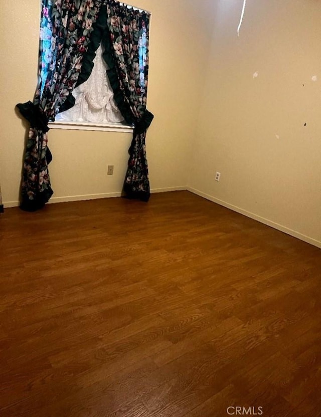 empty room featuring baseboards and wood finished floors