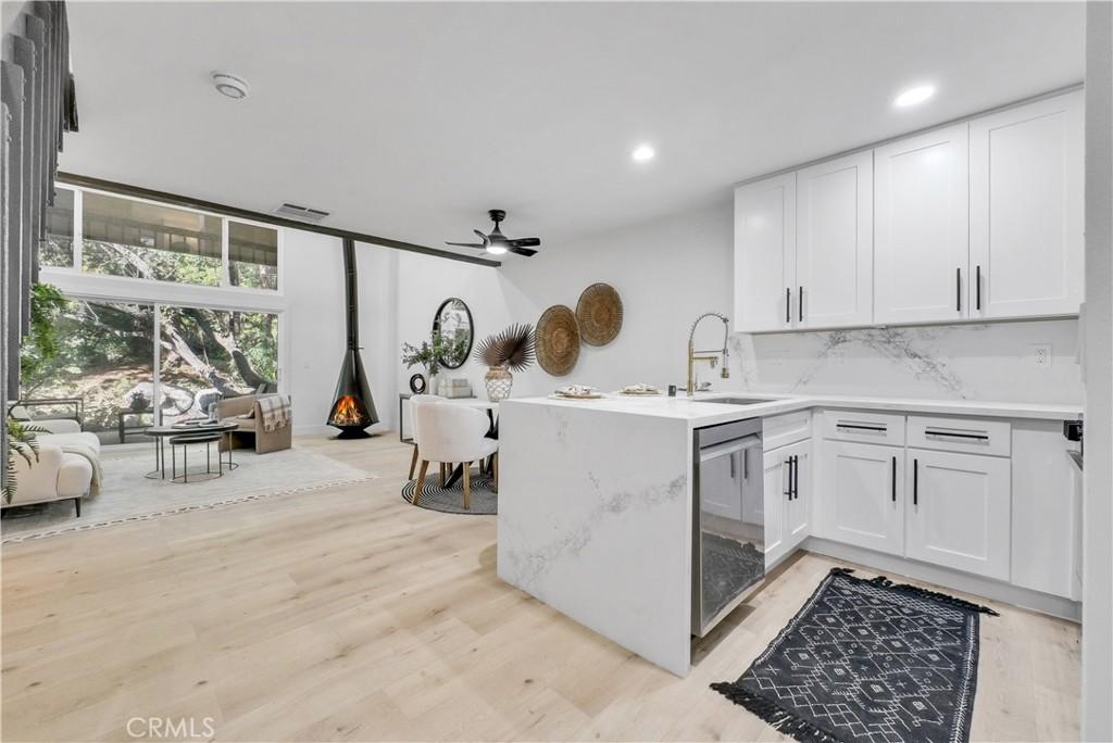 kitchen with tasteful backsplash, kitchen peninsula, ceiling fan, white cabinets, and sink