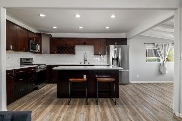 kitchen with appliances with stainless steel finishes, light hardwood / wood-style floors, and a center island