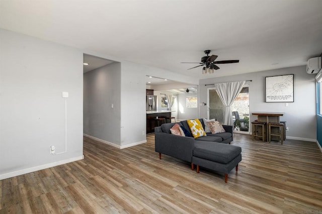 living room featuring hardwood / wood-style flooring, an AC wall unit, and ceiling fan