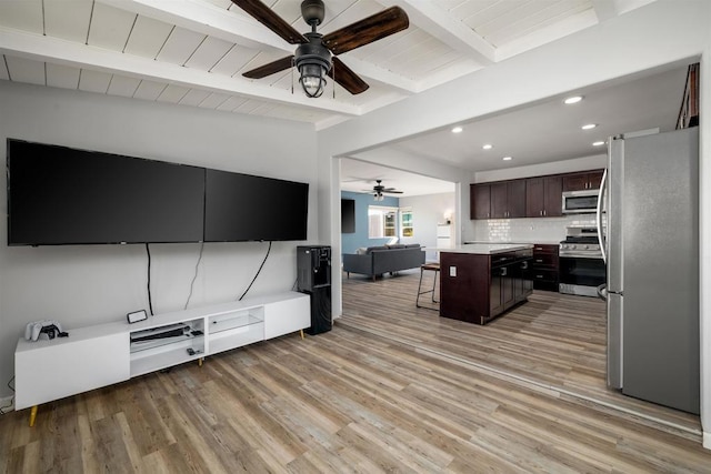 kitchen with a kitchen island, beam ceiling, a breakfast bar area, appliances with stainless steel finishes, and dark brown cabinetry