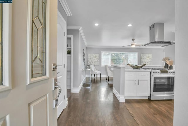 kitchen featuring island exhaust hood, ornamental molding, ceiling fan, white cabinetry, and gas range