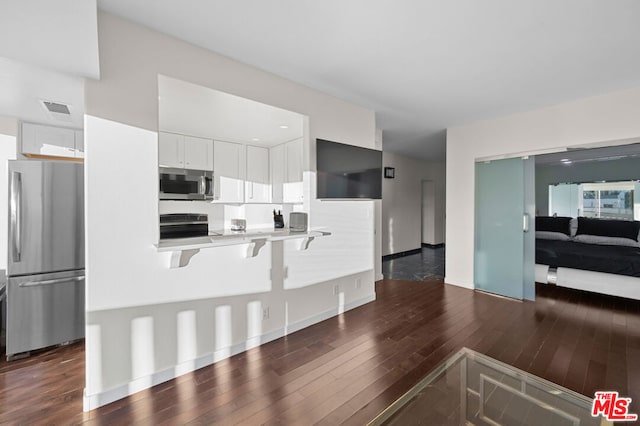 kitchen featuring a kitchen bar, white cabinetry, dark hardwood / wood-style floors, and appliances with stainless steel finishes