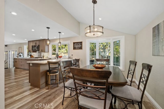 dining space with lofted ceiling, light hardwood / wood-style flooring, and plenty of natural light