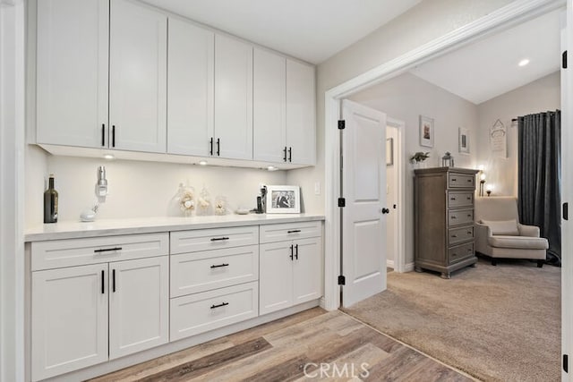 bar with white cabinets and light colored carpet