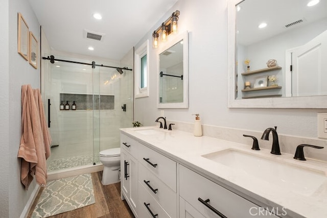 bathroom featuring hardwood / wood-style flooring, toilet, a shower with door, and vanity