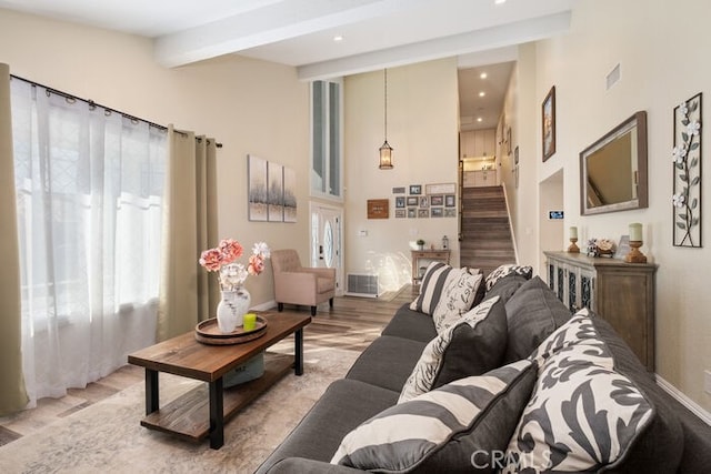 living room featuring a healthy amount of sunlight, beam ceiling, and light hardwood / wood-style floors