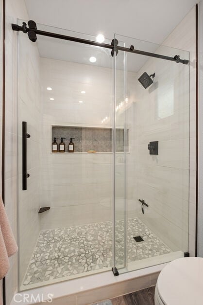 bathroom featuring toilet, hardwood / wood-style floors, and a shower with door