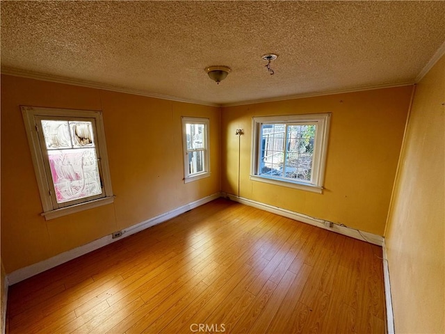 empty room featuring a textured ceiling, light hardwood / wood-style flooring, and crown molding